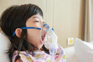 doente pequeno ásia menina inalação com nebulizador para respiratório tratamento foto