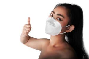 close-up de uma mulher colocando uma máscara respiratória n95 para se proteger de doenças respiratórias transmitidas pelo ar como a gripe covid-19 corona pm2.5 poeira e poluição, feminino gesto de polegar para cima com a mão foto