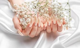 fêmea mãos em uma branco seda fundo com lindo pérola manicure foto