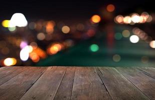 mesa de madeira com luzes da cidade à noite fundo desfocado foto