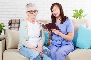 enfermeira lê um livro para uma mulher idosa conceito de reabilitação e lar de idosos domab foto