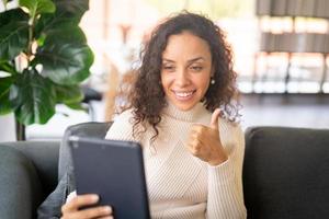 mulher latina videoconferência em tablet com sentimento de felicidade foto