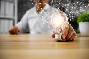 conceito de inovação de ideia e tecnologia, empresário segurando uma lâmpada brilhando com a linha de conexão do poder