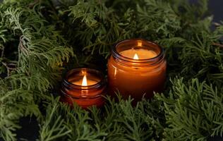 soja vela dentro uma vidro jar. verde Thuja galhos fundo. aromaterapia às lar. perfumado velas decoração foto