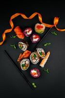 Sushi conjunto com caviar, abacate e salmão. Sushi peças colocada entre pauzinhos, separado em Preto fundo. ásia cozinha. topo visualizar. livre espaço para seu texto. Alto qualidade foto