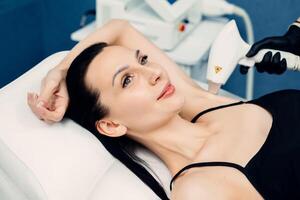 fechar acima do mulher axila área durante procedimento do laser cabelo remoção dentro moderno cosmetologia clínica. conceito do mulheres beleza, cosmetologia, depilação foto