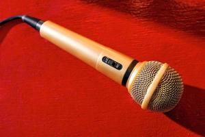 microfone de ouro em madeira vermelha e fundos escuros com muitas luzes
