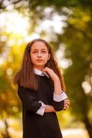 conceito de escola. menina de 11 anos em um vestido no fundo da natureza no outono. foto