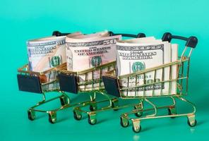 três cestas de compras com dólares em um fundo turquesa. conceito financeiro e de bancos. foto