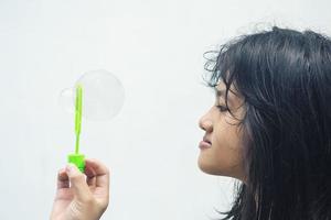 uma garota segurando um fabricante de bolhas e soprando-os para fora. foto