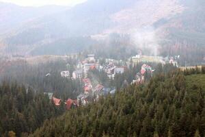 manhã Visão do residente área e casas por aí a dragobrat montanha picos dentro cárpato montanhas, Ucrânia. nublado e nebuloso panorama por aí drahobrat picos foto