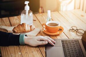 mulheres usando computador portátil trabalhando e limpar \ limpo mãos com álcool beber café copo quente às casa foto