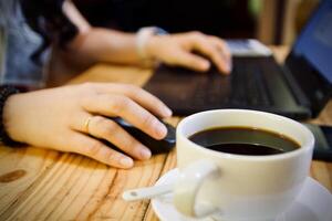 mulheres usando computador portátil trabalhando e beber café copo quente às casa foto