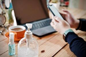 mulheres usando computador portátil trabalhando e limpar \ limpo mãos com álcool beber café copo quente às casa foto