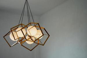 uma lâmpada redonda com uma moldura retangular de ferro suspensa do teto, iluminando em ouro. conceito de interior. foto