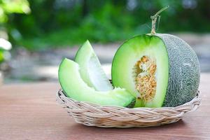 melão verde brilhante é colocado em uma cesta de vime branca em um fundo de jardim desfocado. fatiado de frutas de melão de melada ou foco de concept.selective de saúde. foto
