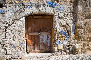 paredes antigas e porta de entrada de madeira na cidade velha de Rodes, Grécia foto