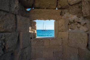 bela vista do mar mediterrâneo com um navio, emoldurada por uma janela nas muralhas da cidade de rhodes. Grécia. foto