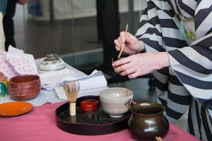 mulher japonesa irreconhecível durante a preparação da cerimônia do chá. mãos segurando uma tigela. foto