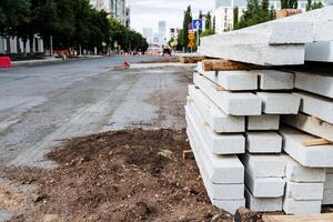 branco concreto blocos para pavimentação lajes estão empilhado em a rua, uma borda da calçada para uma pedestre caminho foto