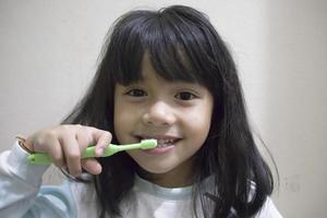 menina escovando os dentes com escova de dentes foto