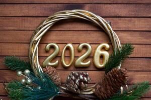 feliz Novo ano dourado números 2026 em acolhedor festivo Castanho de madeira fundo com lantejoulas, neve, luzes do guirlandas. saudações, cartão postal. calendário, cobrir foto
