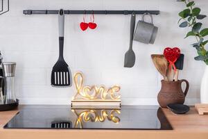 o interior da cozinha da casa é decorado com corações vermelhos para o dia dos namorados. decoração na mesa, fogão, utensílios, clima festivo em ninho familiar foto
