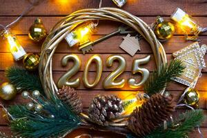 Novo ano casa chave com chaveiro chalé em festivo Castanho de madeira fundo com número 2025 dentro guirlanda, luzes do guirlandas. comprar, construção, realocação, hipoteca, seguro foto