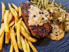 francês bife de pimenta com verde Pimenta verde feijões e pommes batatas fritas foto