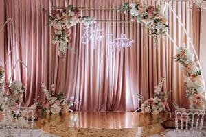 uma belas decorado Lugar, colocar para a Casamento cerimônia do a noiva e noivo dentro uma moderno estilo. Casamento arco fez do branco e Rosa fresco flores lindo decorativo cadeiras e dourado pernas foto