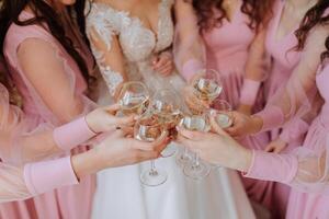 fechar-se do a noiva e dela damas de honra segurando uma vidro do champanhe. Casamento celebração dentro a círculo do mais próximo amigos foto