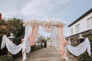 casamento. Casamento cerimônia. arca. a arco decorado com Rosa e branco flores carrinhos dentro a pátio, dentro a área do a Casamento cerimônia foto