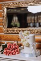 uma ampla luxuoso multicamadas Casamento bolo é decorado com fresco branco rosa flores dentro a banquete corredor. Casamento sobremesa debaixo a tarde claro. Casamento decoração. foto