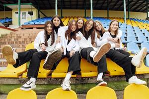 uma grupo do muitos feliz adolescentes vestido dentro a mesmo equipamento tendo Diversão e posando dentro uma estádio perto uma faculdade. conceito do amizade, momentos do felicidade. escola amizade foto