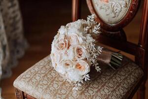 casa estilo. Casamento ramalhete do creme e Rosa flores em uma cadeira às casa debaixo luz do dia. detalhes do a noiva e noivo. foto