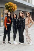 grupo do sorridente e feliz Adolescência amigos vestindo casual roupas gastos Tempo junto, posando e falando com cada de outros perto Faculdade construção em outono dia. foto