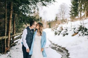 uma lindo casal é caminhando dentro uma inverno pinho floresta cercado de uma muitos do neve. a noiva dentro uma branco Casamento vestir, a noivo dentro uma branco camisa e colete. inverno Casamento conceito. foto