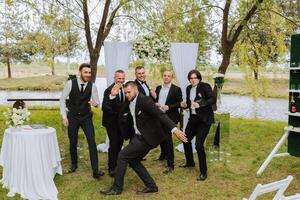 alegre, jovem, enérgico testemunhas do a noivo Próximo para a noivo. amigos felicitar a noivo. noivo e dele engraçado amigos tendo Diversão em a Casamento dia do a recém-casados. foto