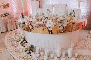 romântico mesa configuração dentro uma restaurante para uma feriado. Casamento decoração para a recém-casados às a banquete. floricultura do fresco flores e velas, boho estilo. refeições para a noiva e convidados. foto