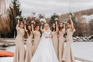 a noiva e dela damas de honra pose segurando buquês e olhando às a noiva. inverno Casamento foto