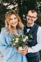 inverno Casamento dentro a montanhas. retrato do uma feliz e sorridente noiva e noivo contra a fundo do uma inverno floresta. lindo noiva e noivo ternamente abraçar. moderno inverno casamento. foto