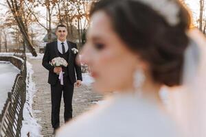 inverno casamento. feliz casal caminhando dentro Casamento roupas abraçando e sorridente dentro uma inverno parque coberto com neve em seus Casamento dia. inverno amor história do uma lindo casal dentro Nevado inverno clima foto