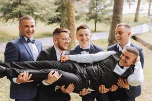 alegre, jovem, enérgico testemunhas do a noivo Próximo para a noivo. amigos felicitar a noivo. noivo e dele engraçado amigos tendo Diversão em a Casamento dia do a recém-casados. foto