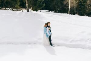 uma lindo casal é em pé dentro uma inverno pinho floresta, cercado de uma muitos do neve. a noiva dentro uma branco Casamento vestir, a noivo dentro uma branco camisa e colete. inverno Casamento conceito. foto