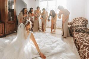 damas de honra dentro creme vestidos e a noiva pose dentro a da noiva sala. preparação. manhã do a noiva foto