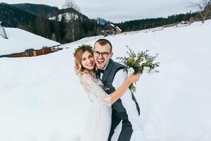 jovem casal noiva e noivo jogando dentro inverno natureza em a fundo do Nevado montanhas. jogando bolas de neve, pulando, abraçando. ter uma ótimo tempo. rindo foto