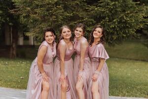 grupo retrato do a noiva e damas de honra. noiva dentro uma Casamento vestir e damas de honra dentro Rosa ou pó vestidos e segurando à moda buquês em a Casamento dia. foto