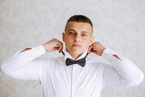 uma à moda noivo é amarrar dele gravata, preparando para a Casamento cerimônia. do noivo manhã. uma homem de negocios desgasta uma gravata. a noivo é obtendo pronto dentro a manhã antes a Casamento cerimônia. foto