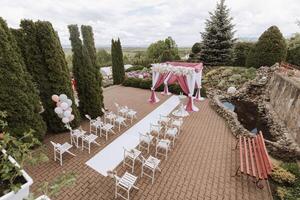 Casamento decoração. muitos branco cadeiras e uma branco caminho. uma branco e Rosa arco decorado com flores preparação para a Casamento cerimônia. celebração foto