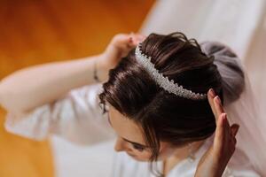 à moda Penteado do a noiva com uma tiara em dela cabeça. uma fechar-se do a Penteado do uma lindo noiva. a conceito do uma motivo em a tema do uma cabeleireiro, Casamento e Casamento preparações. foto